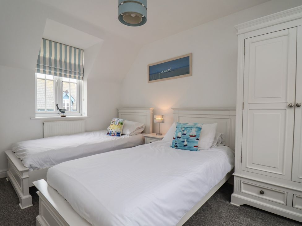 A bedroom with two beds and a wardrobe at Coastal Cottage The Bay near Filey