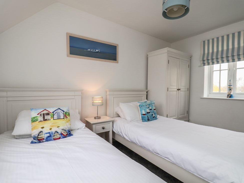 A bedroom with two beds and a wardrobe at Coastal Cottage The Bay near Filey