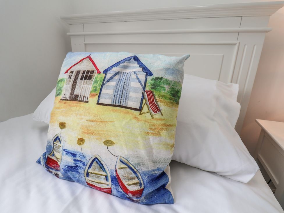 A pillow featuring beach huts and boats on a bed at Coastal Cottage The Bay near Filey