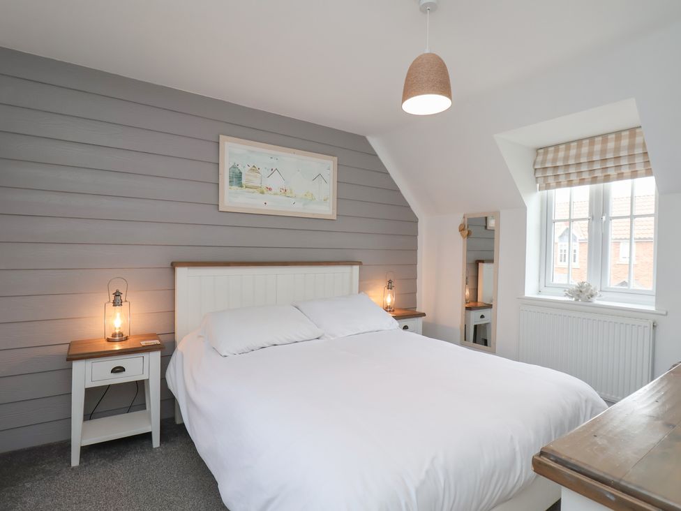 A bedroom with a bed and nightstand at Coastal Cottage The Bay near Filey