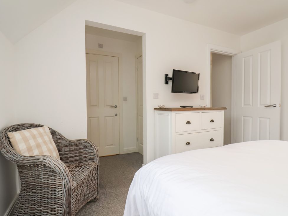 A bedroom with a chair and television on the wall at Coastal Cottage The Bay near Filey