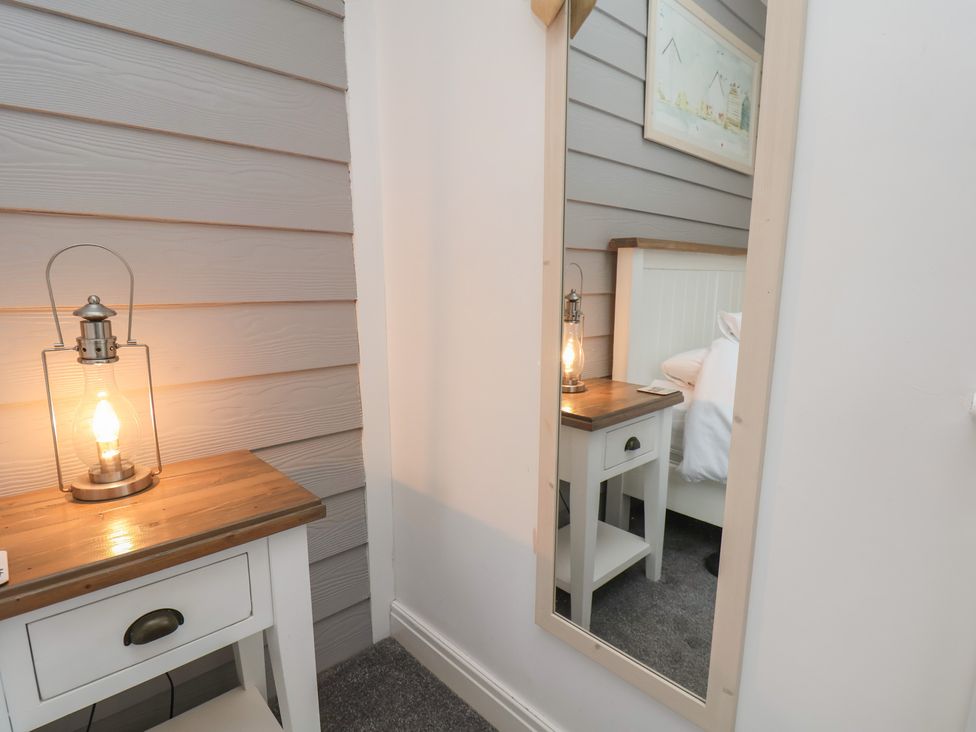 A bedroom with a mirror and a bedside table lamp at Coastal Cottage The Bay near Filey
