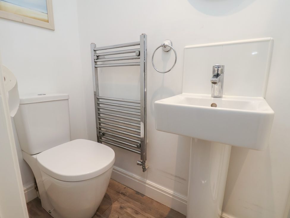A bathroom with a toilet, basin, and towel rail at Coastal Cottage The Bay near Filey