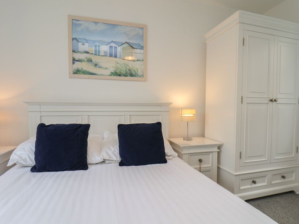 A bedroom with a bed, nightstand, lamp, and wardrobe at Coastal Cottage The Bay near Filey