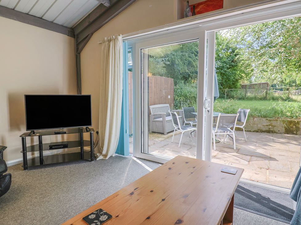 A living room with a television and coffee table at Brookfield Lodge in Drimpton