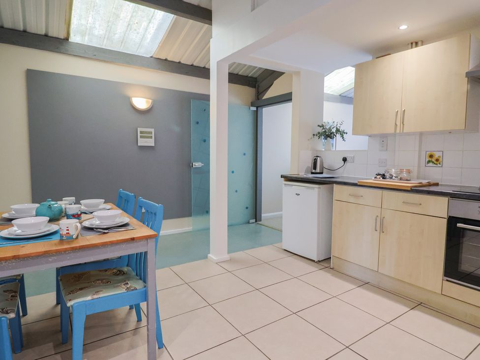 A kitchen with a dining table and blue chairs at Brookfield Lodge in Drimpton