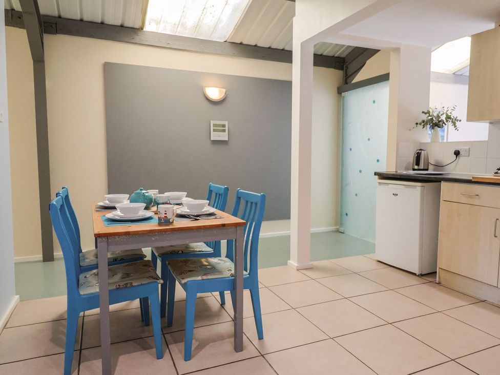 A dining room with a table and blue chairs at Brookfield Lodge Drimpton