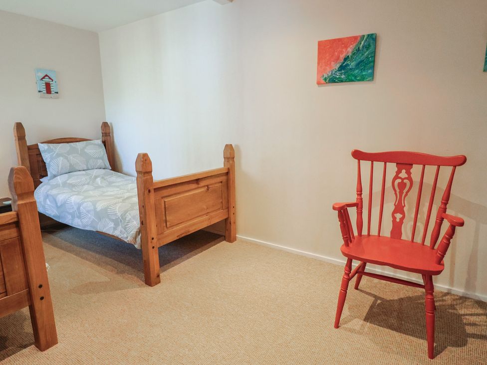 A bedroom with beds and a red chair at Brookfield Lodge in Drimpton