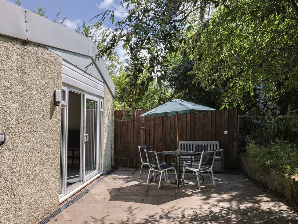 A garden with a table and chairs under an umbrella at Brookfield Lodge in Drimpton