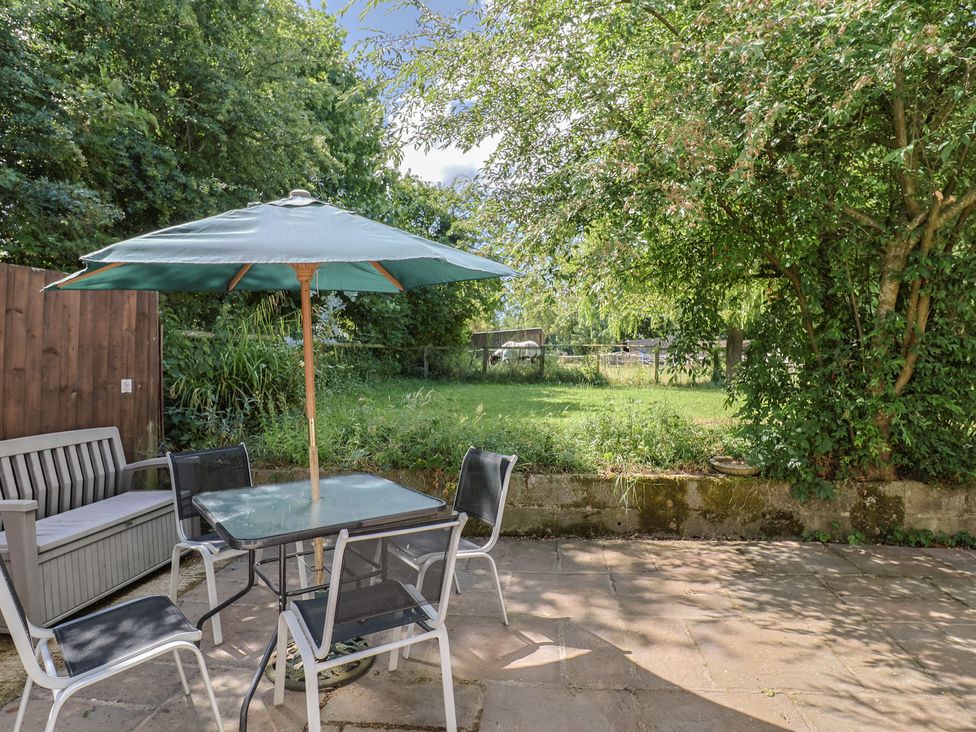 A garden with a patio set and umbrella at Brookfield Lodge in Drimpton