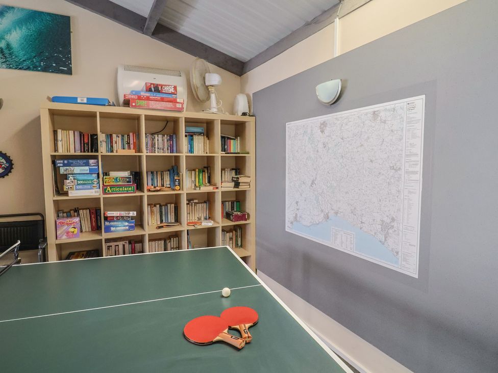 A games room with a table tennis table and bookshelf at Brookfield Lodge in Drimpton