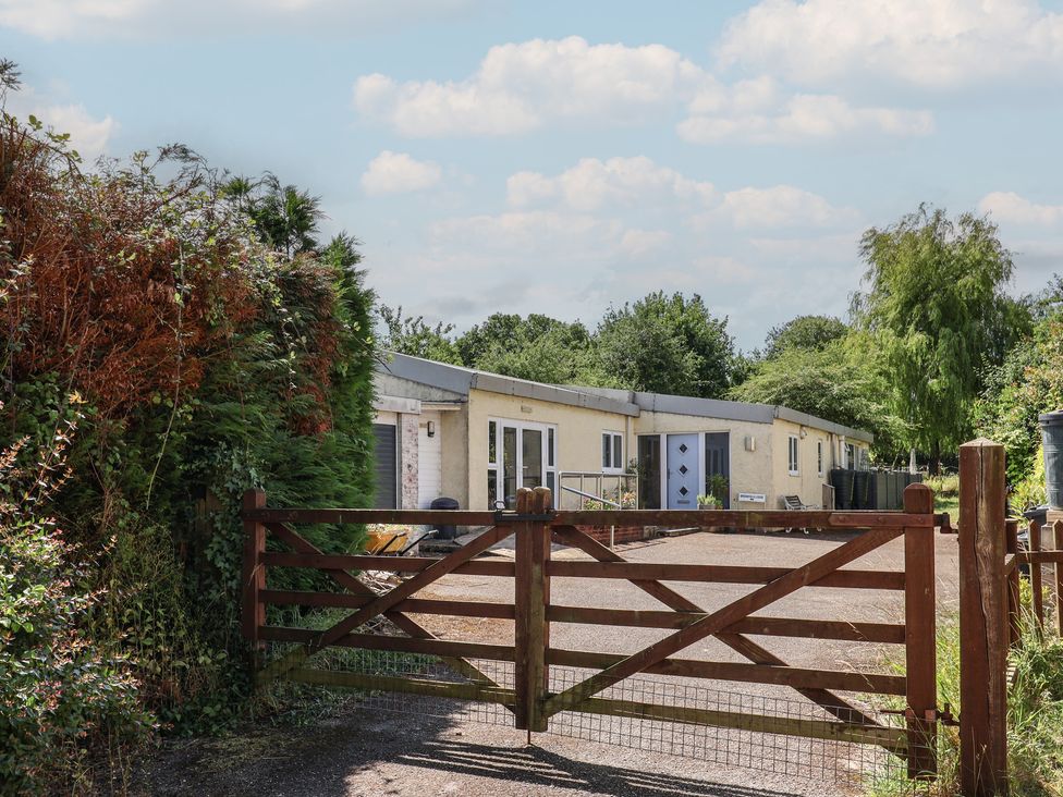 A building viewed through a wooden gate at Brookfield Lodge in Drimpton