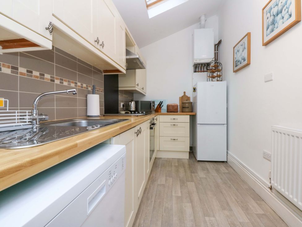 A kitchen with a sink and appliances at 2 Argoed Llanbedrog