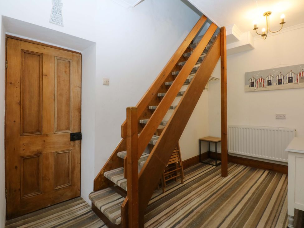 A hallway with a wooden door and stairs at 2 Argoed Llanbedrog