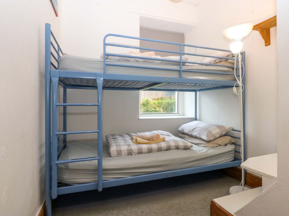 A bedroom with a bunk bed and a side lamp at 2 Argoed Llanbedrog