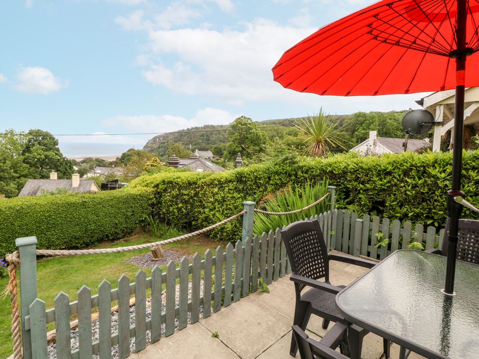 A garden with a table and chairs under an umbrella at 2 Argoed Llanbedrog