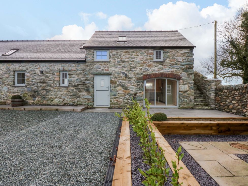 An outdoor area with a stone wall and gravel pathway at Storws Tanrallt