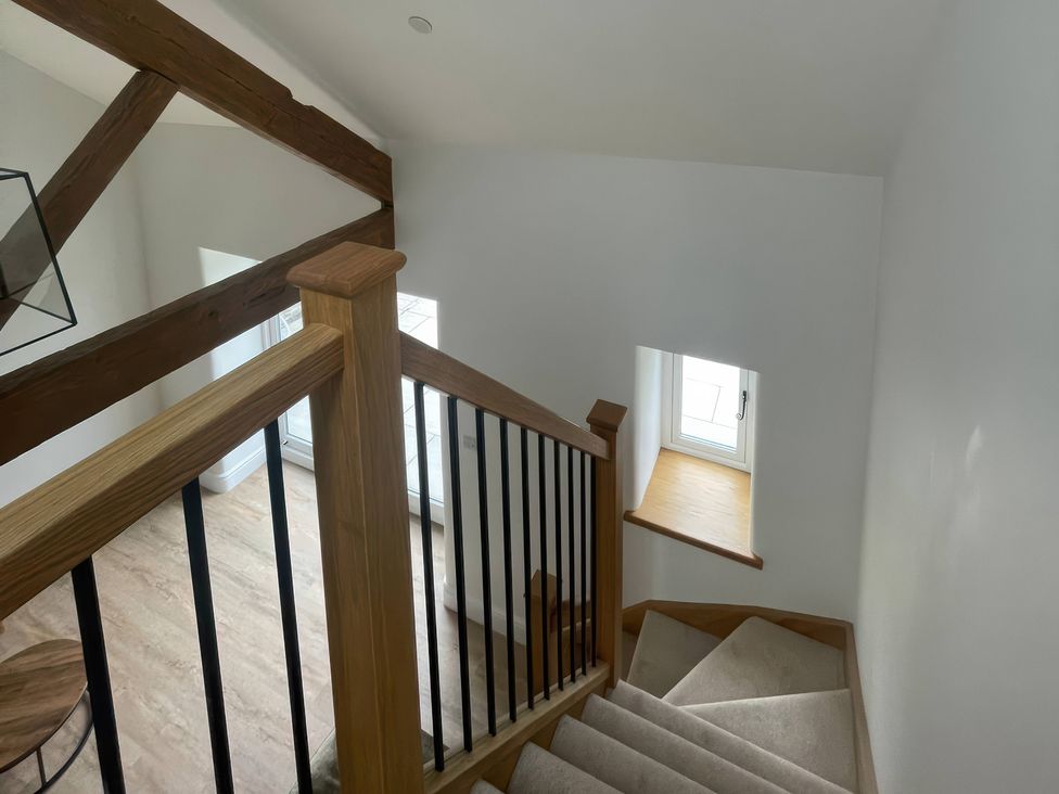 A staircase with wooden beams and a window at Storws Tanrallt Llanfachraeth