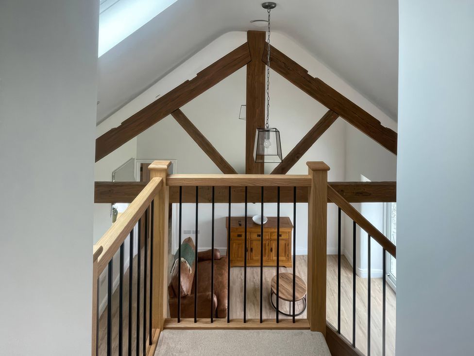 A living room view from above with a wooden railing at Storws Tanrallt Llanfachraeth
