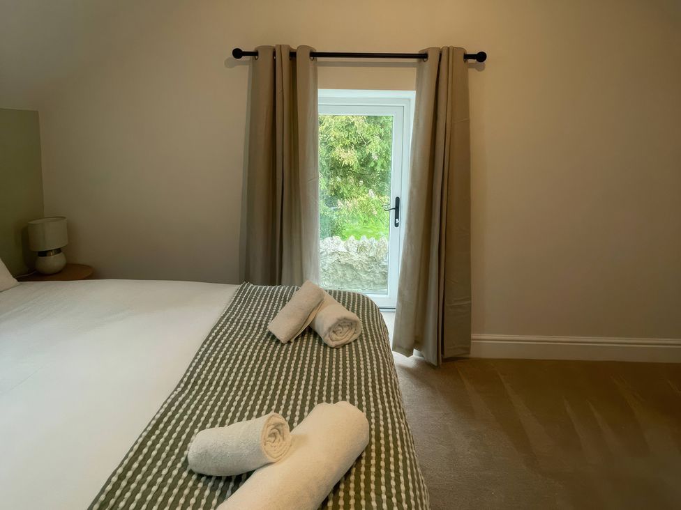 A bedroom with a bed and window at Storws Tanrallt Llanfachraeth