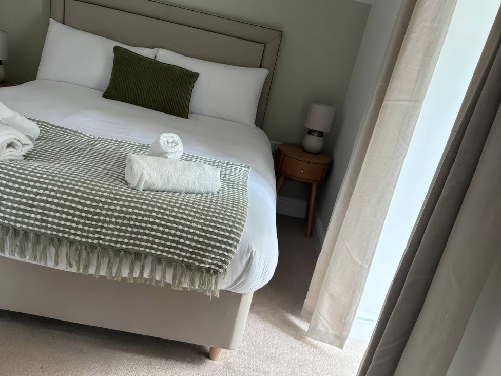 A bedroom with a bed and towels at Storws Tanrallt Llanfachraeth