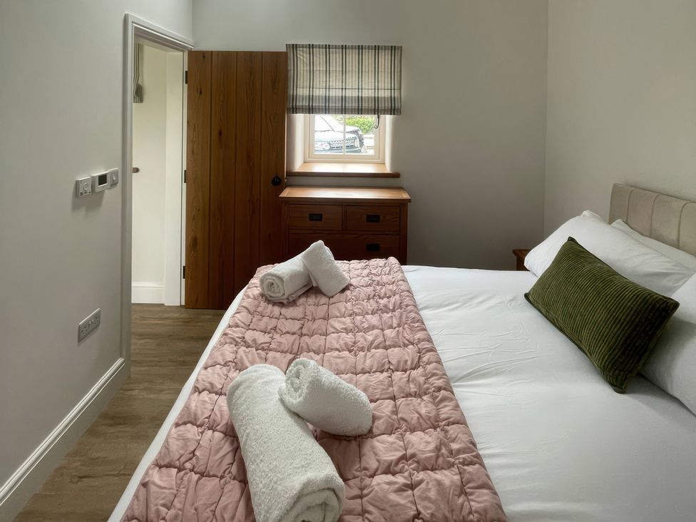A bedroom with a bed and wooden furniture at Storws Tanrallt Llanfachraeth