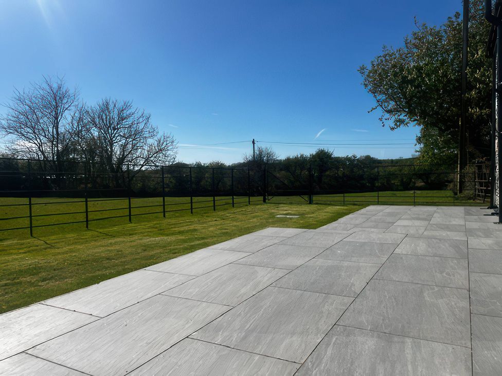A garden with a patio and grass at Storws Tanrallt in Llanfachraeth