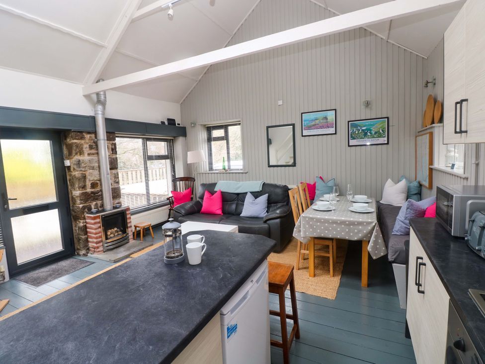 A living room with a sofa and dining area at Brewery Cottage in Saundersfoot