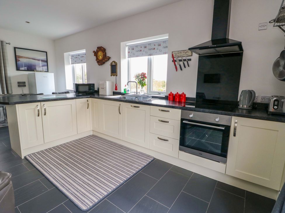 A kitchen with cabinets, sink, and appliances at Hafod Wen in Pentraeth