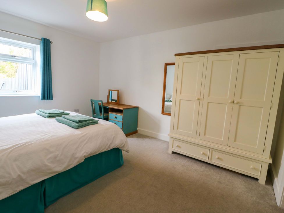 A bedroom with a bed and a wardrobe at Hafod Wen in Pentraeth