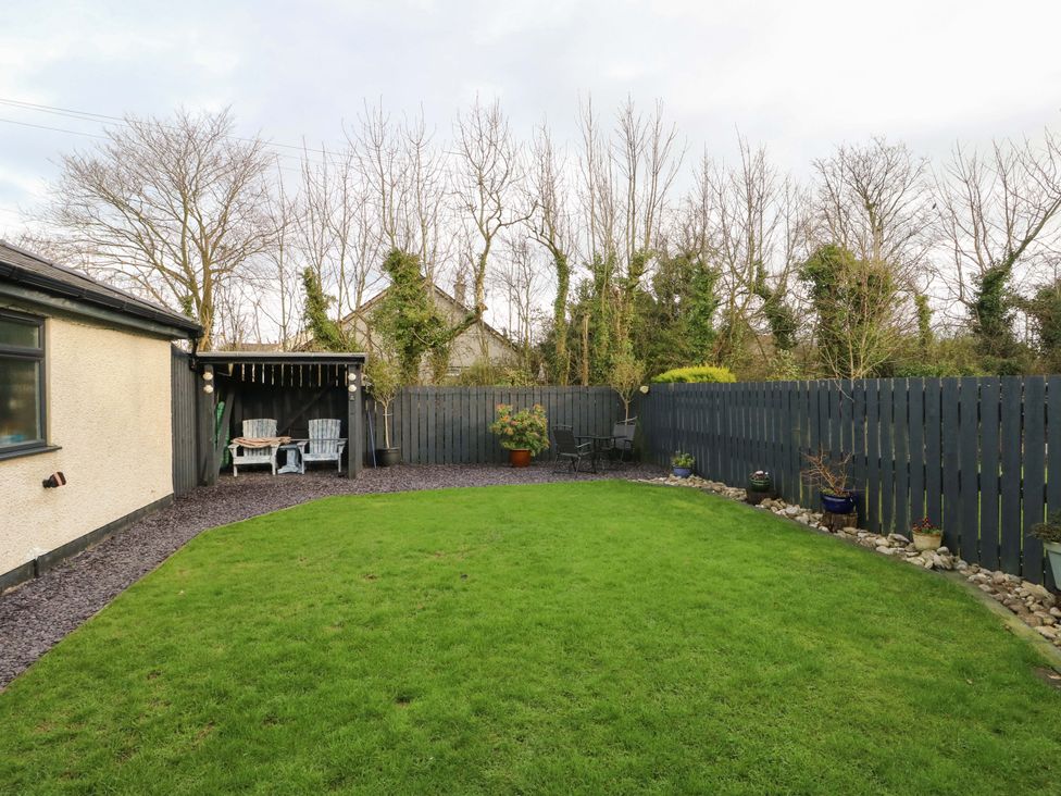 A garden with grass and seating area at Hafod Wen Pentraeth