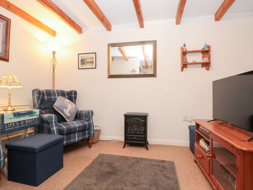 A living room with an armchair and television at The Old Cottage in Staithes
