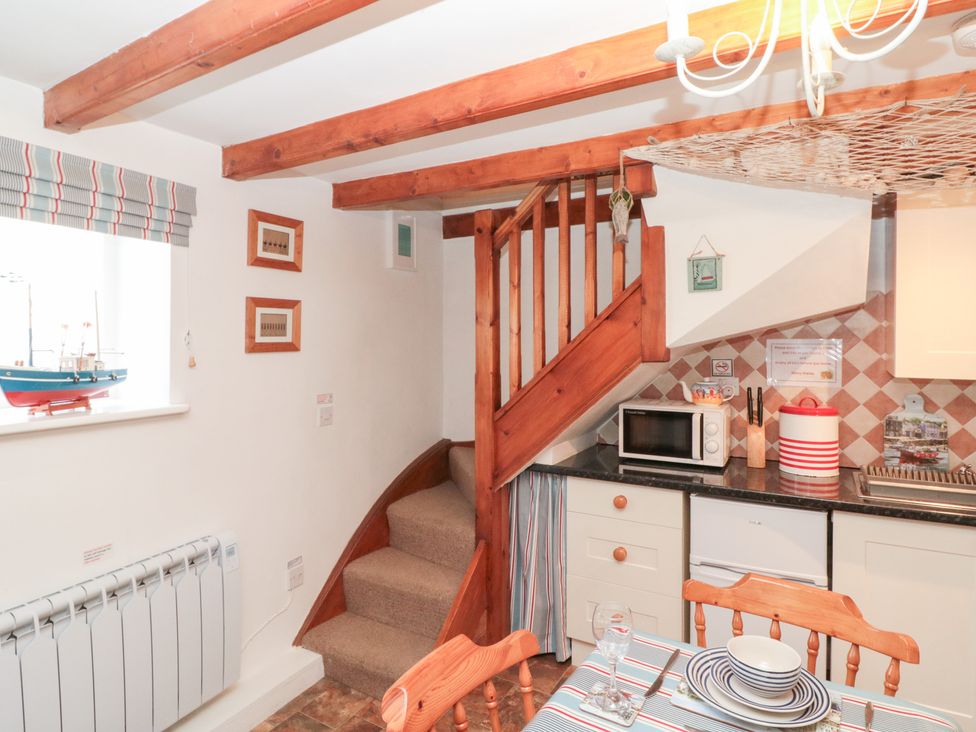 A kitchen with a staircase and dining table at The Old Cottage in Staithes