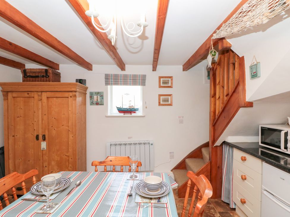 A kitchen with a dining table and wooden cabinet at The Old Cottage in Staithes