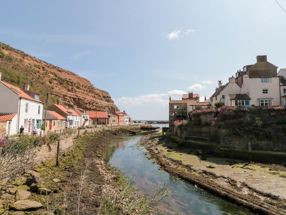 A view of houses alongside a river with cliffs at The Old Cottage in Staithes