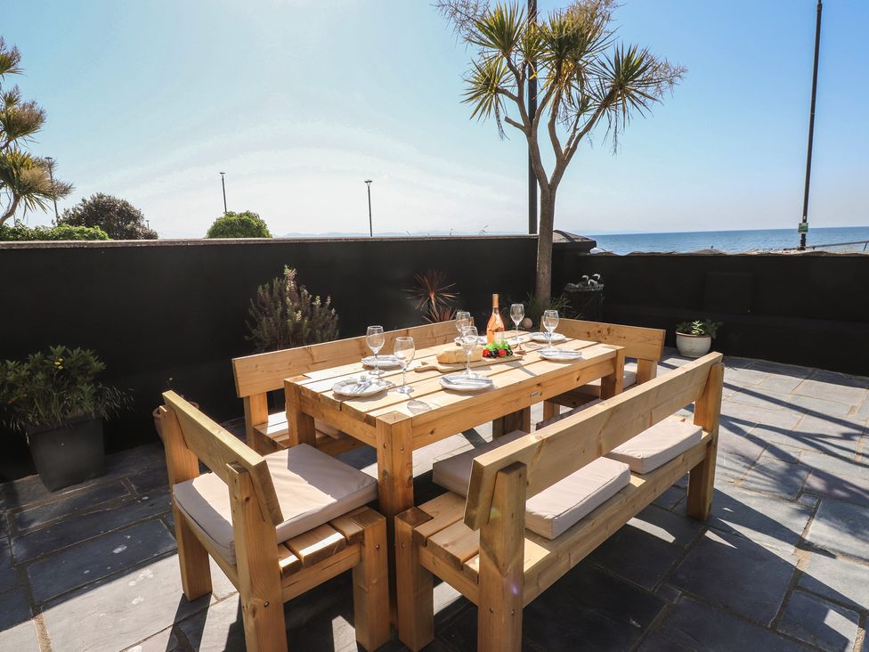 An outdoor dining area with a wooden table and benches at Wavecrest in Pwllheli