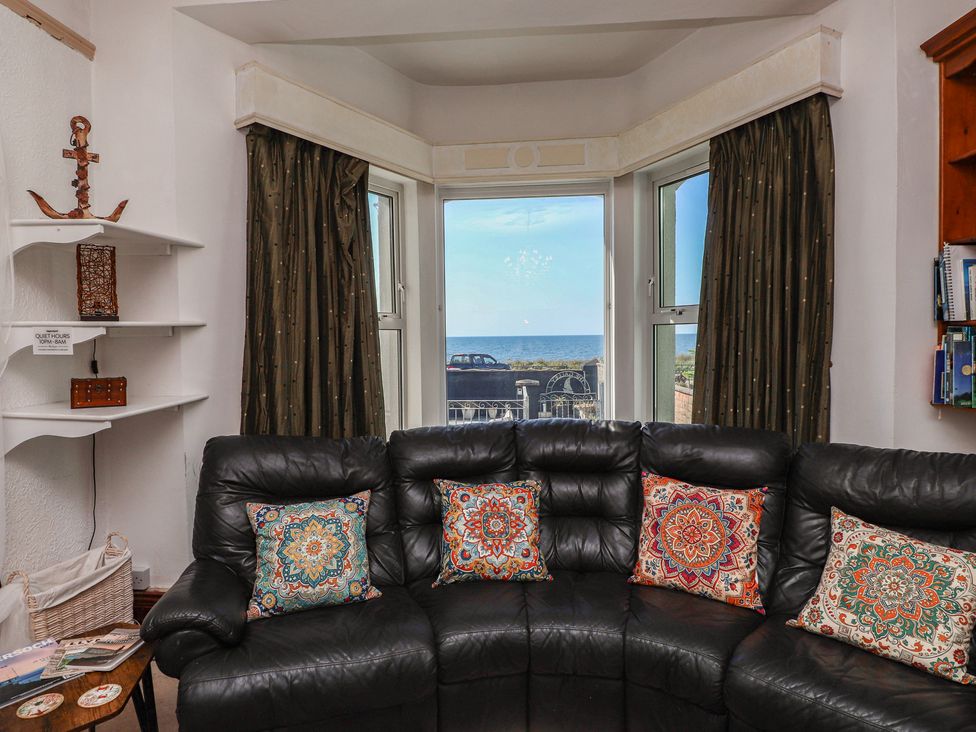 A living room with a couch and a view of the sea at Wavecrest in Pwllheli
