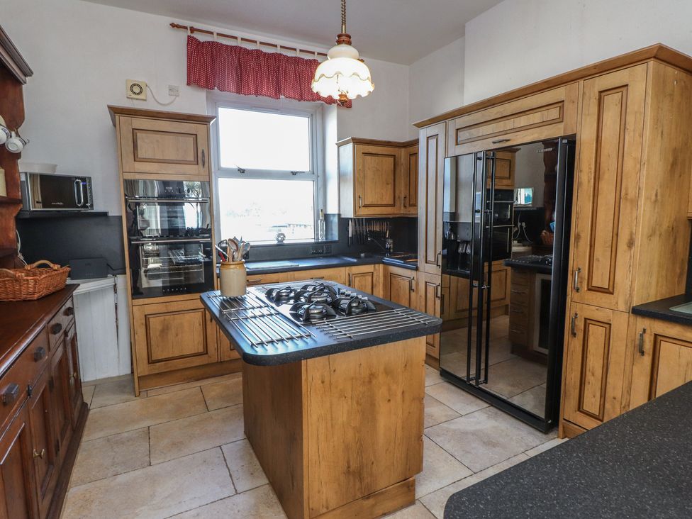 A kitchen with wooden cabinets and appliances at Wavecrest in Pwllheli