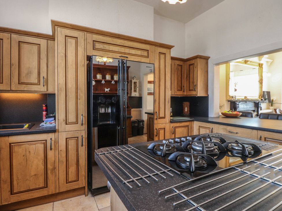 A kitchen with wooden cabinets and a refrigerator at Wavecrest in Pwllheli