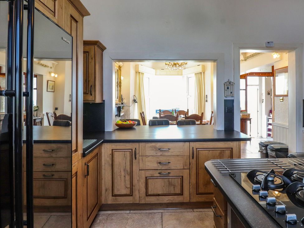 A kitchen with cabinets and a dining area at Wavecrest in Pwllheli