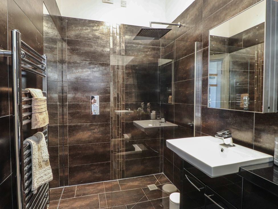 A bathroom featuring a shower, sink, and towel warmer at Wavecrest in Pwllheli