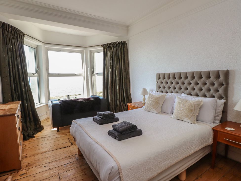 A bedroom with a bed and windows at Wavecrest in Pwllheli