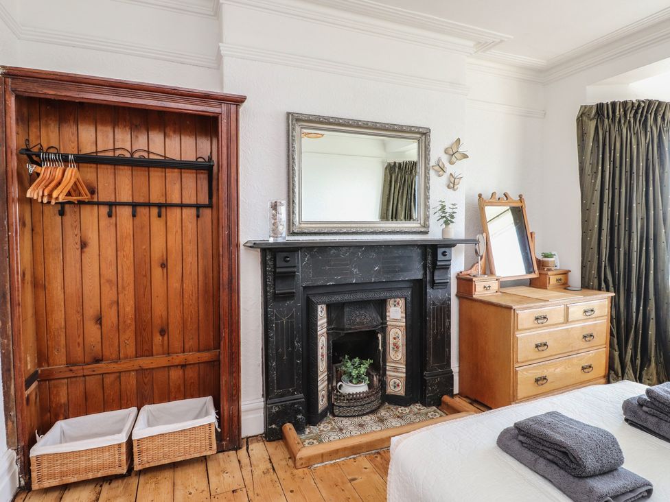 A bedroom with a wardrobe and a fireplace at Wavecrest in Pwllheli