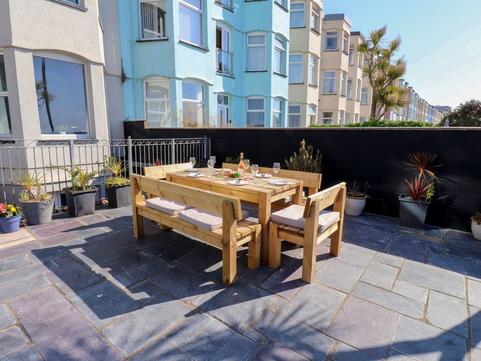 An outdoor dining area with a wooden table and chairs at Wavecrest in Pwllheli