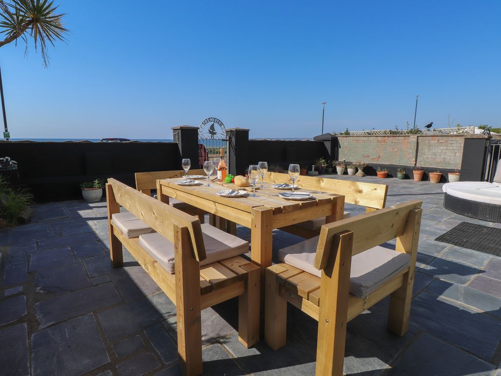 An outdoor dining area with a wooden table and chairs at Wavecrest in Pwllheli