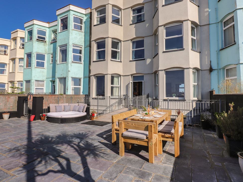 An outdoor patio with seating and dining table at Wavecrest in Pwllheli
