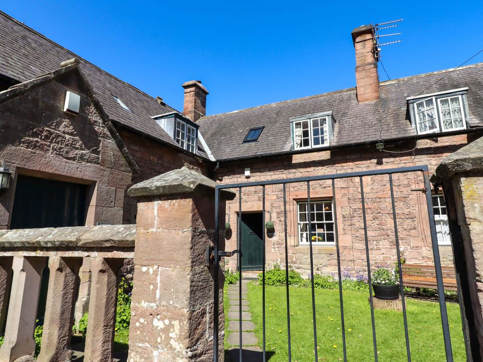 A garden area with stone walls and a gate at Gamekeepers Cottage in Chillingham near Chatton
