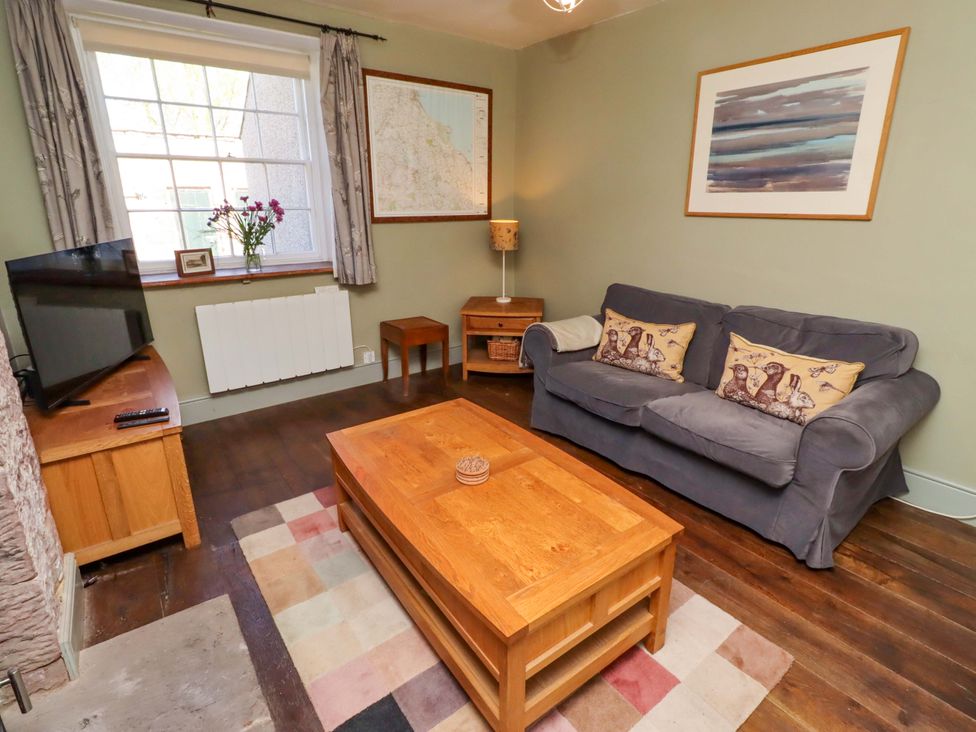 A living room with a sofa and coffee table at Gamekeepers Cottage in Chillingham near Chatton