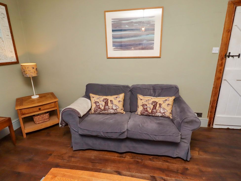A living room with a sofa and side table at Gamekeepers Cottage in Chillingham near Chatton