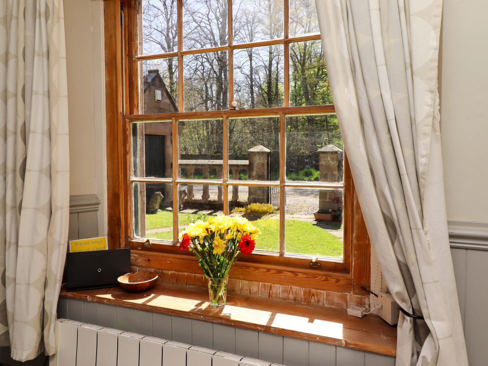 A window with flowers on the sill at Gamekeepers Cottage in Chillingham near Chatton